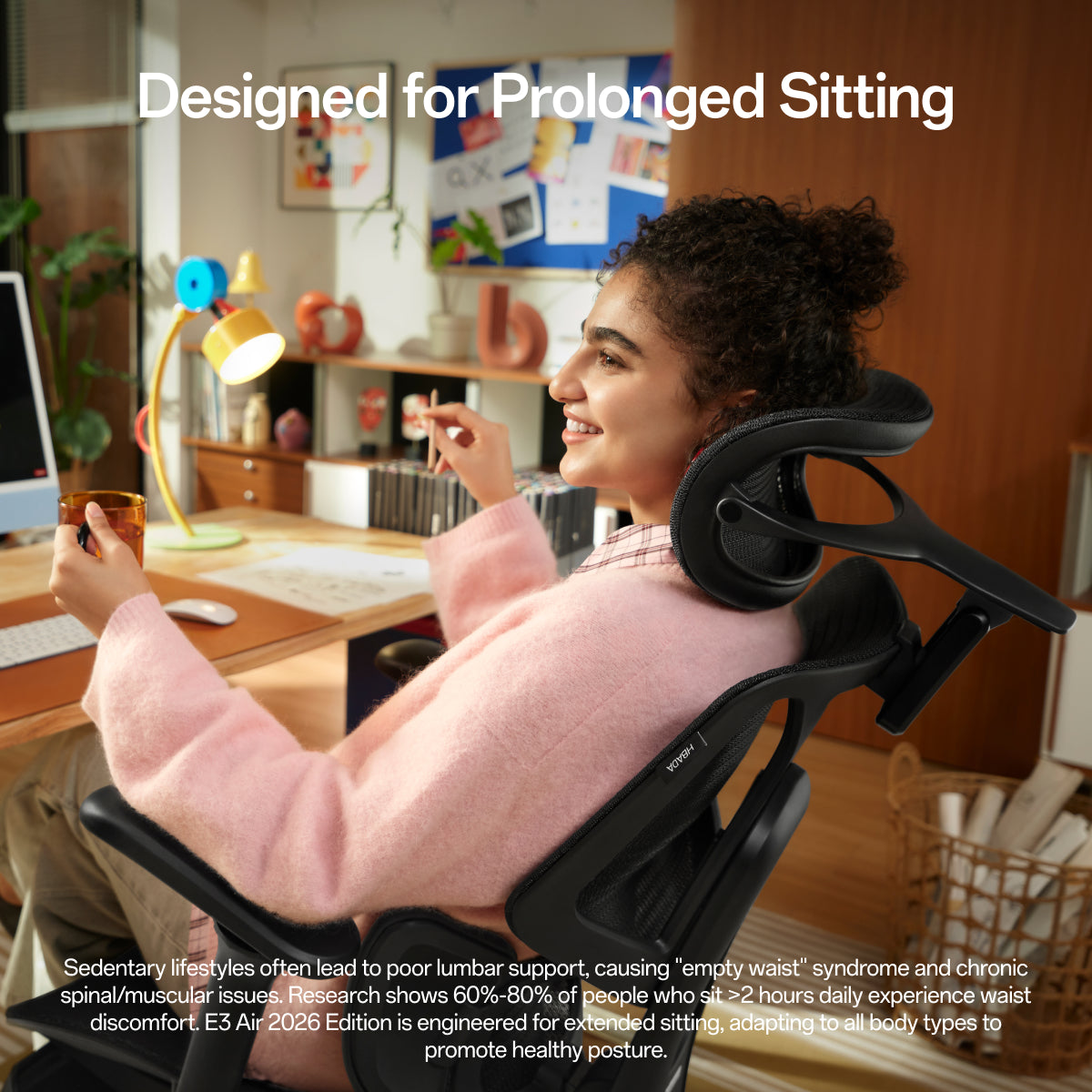 A woman in a pink sweater sits in a black ergonomic office chair in a home office setting, with text reading 'Designed for Prolonged Sitting' and descriptive copy at the bottom about sedentary lifestyles and waist support.~scene