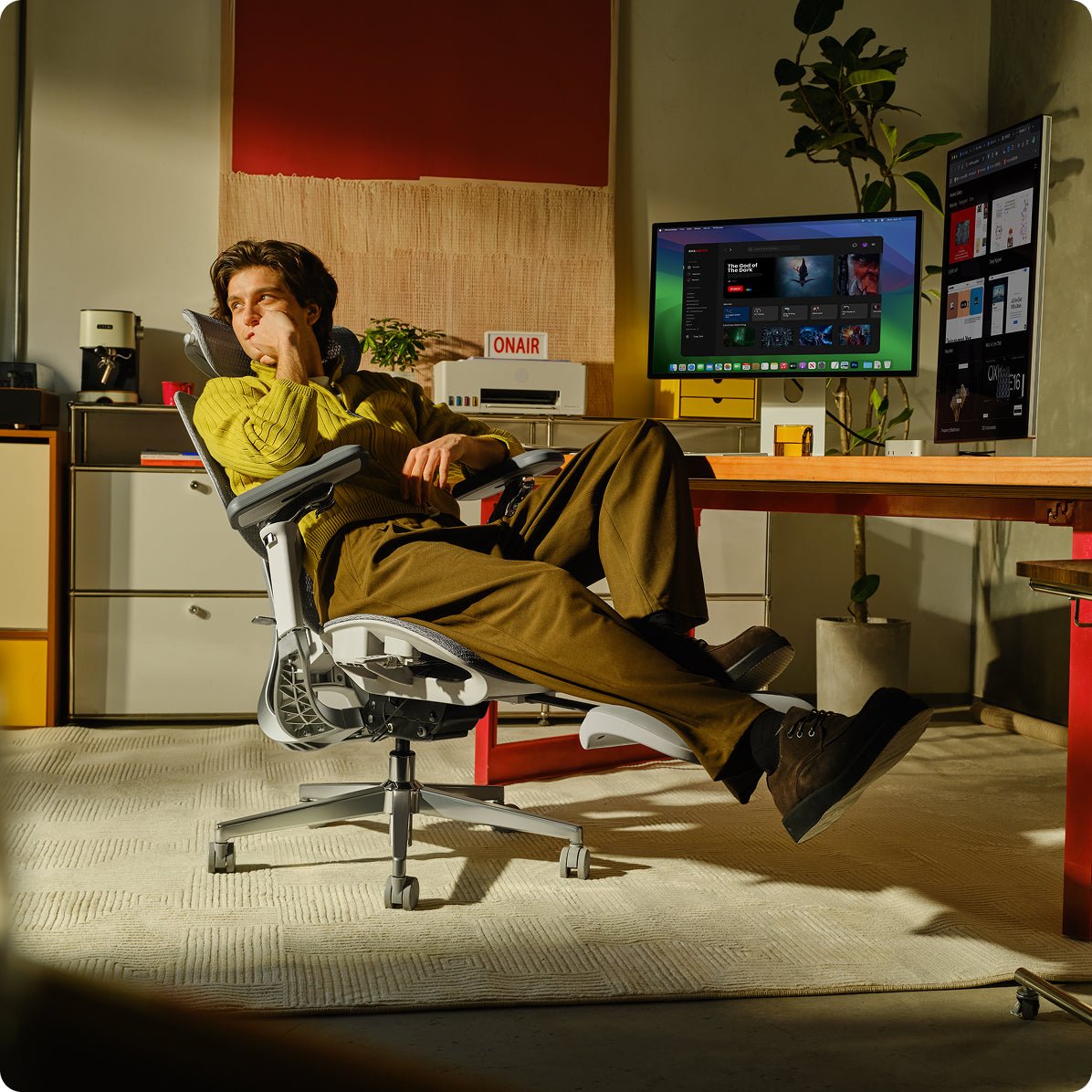 Person sitting in a modern office chair in a room with a computer setup~scene