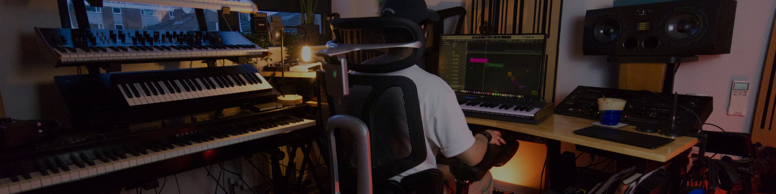Person seated in an HBADA ergonomic office chair at a music production desk